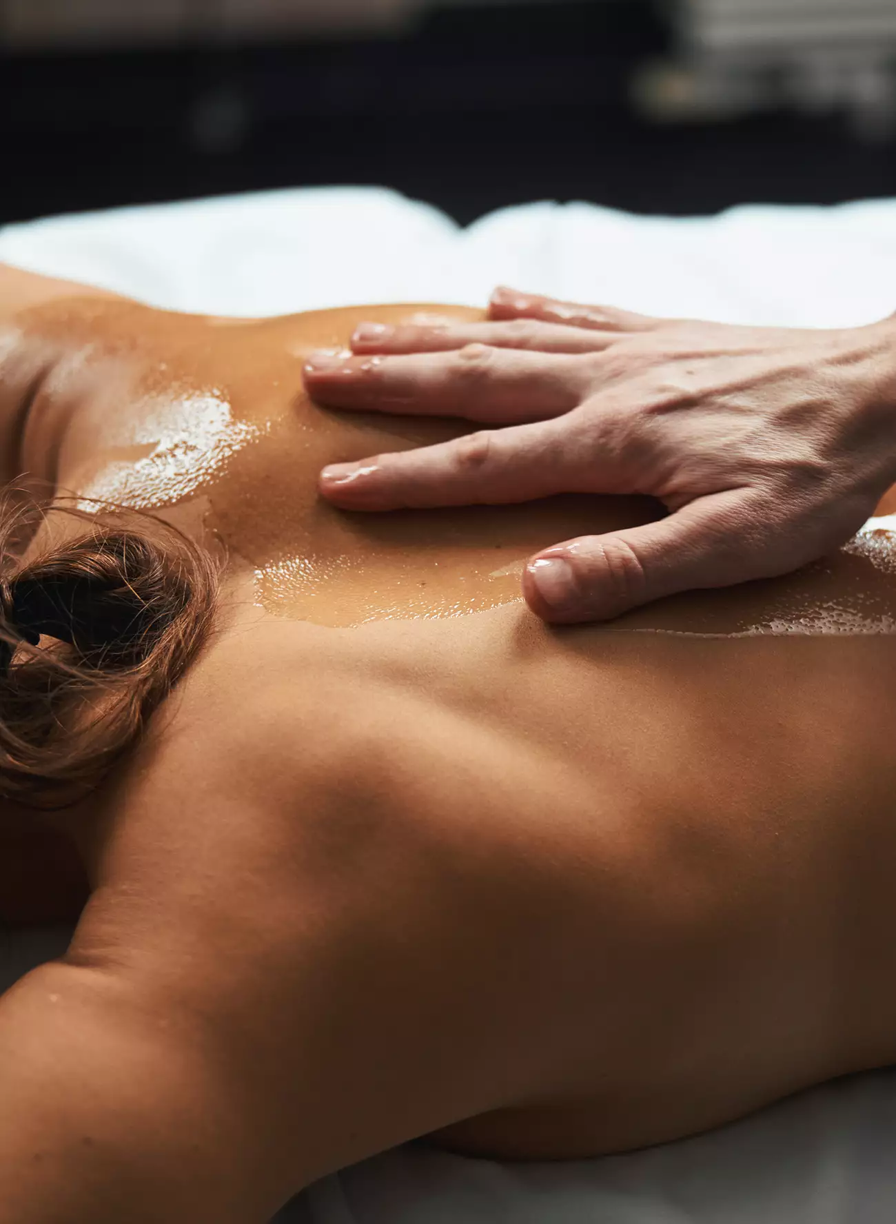 Hand massaging oiled upper back