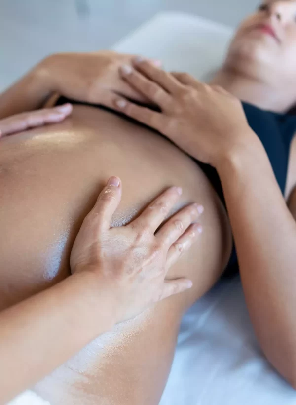 Massage therapist hands on the belly of pregnant woman during pregnancy massage