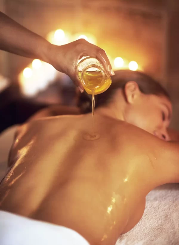 Pouring oil over the back of female during massage treatment