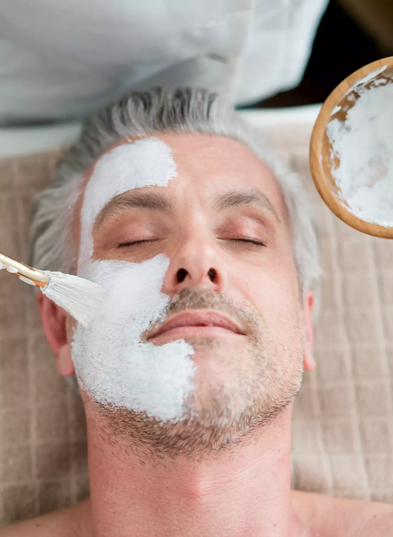 Face mask skin care being brushed on a mans face during a Mens Facial