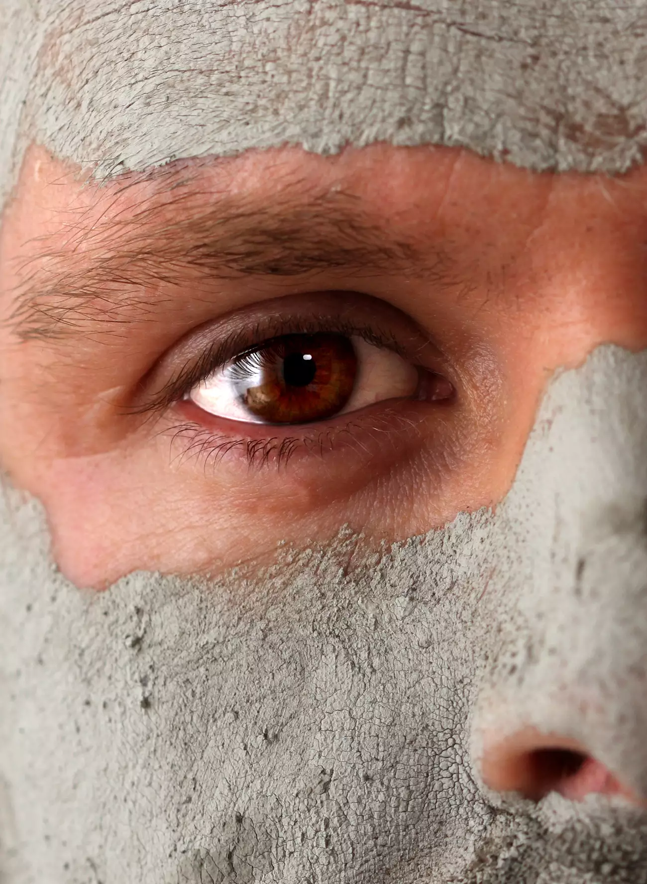 Part of a mans face with a clay face mask experienced during a Mens Facial