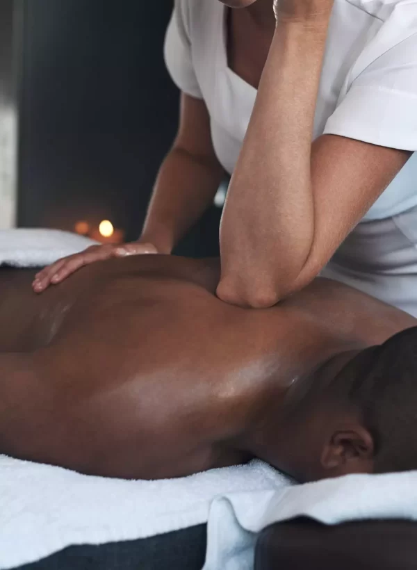 Massage therapist using elbow to massage back on man