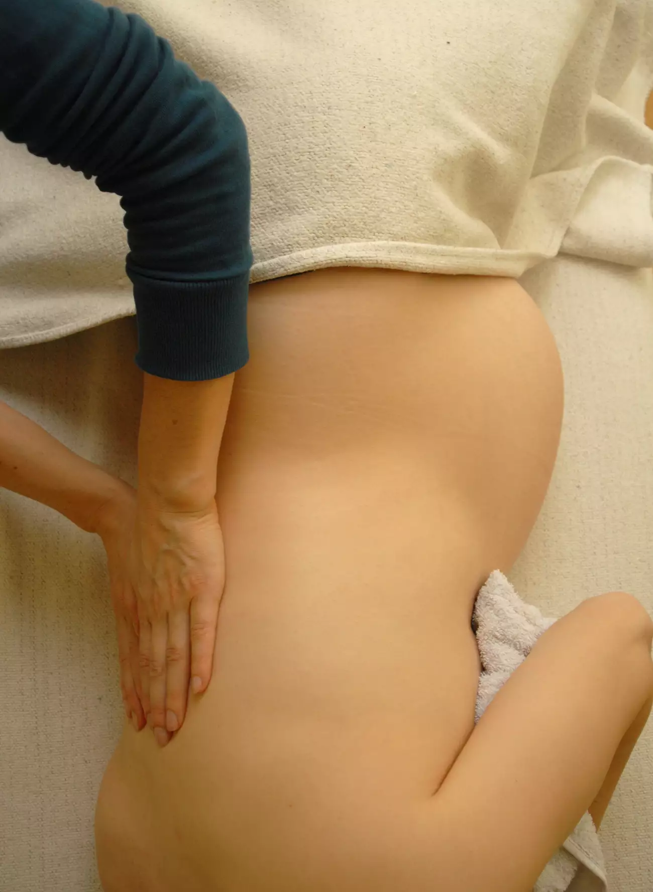 Pregnant woman lying on her side receiving pregnancy massage