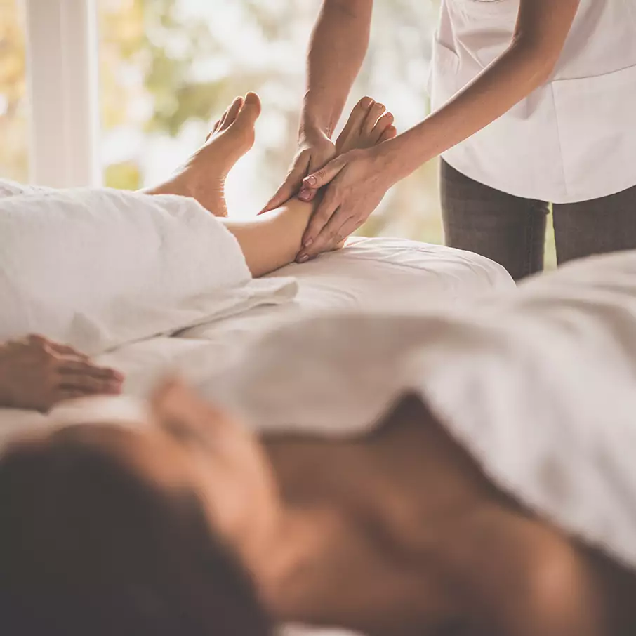 a couple lying on a massage table enjoying a foot massage by a therapist