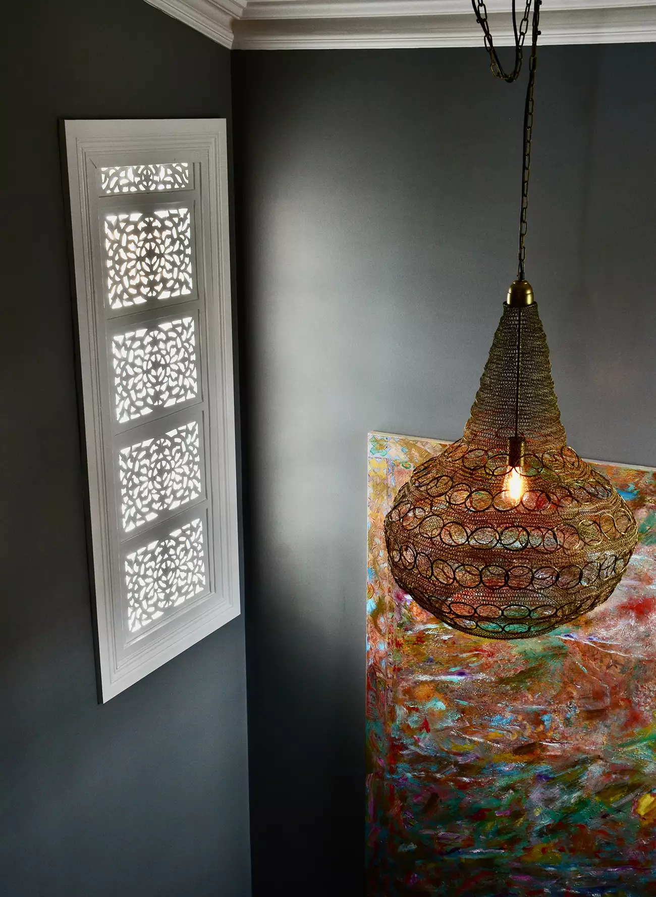 Window with oriental screen in stairwell with metal pendant light and artwork