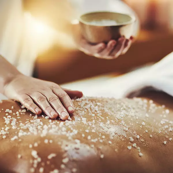 Salt scrub applied to the back of body during a treatment
