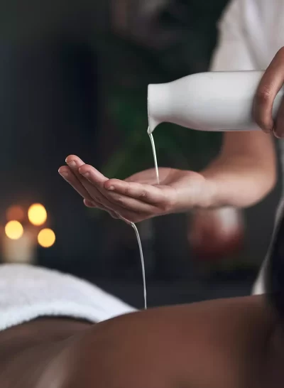 Warmed massage oil being poured on hand and onto back